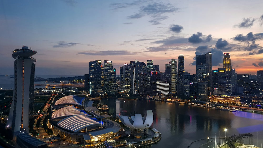 ingapore Marina Bay skyline at dusk with Marina Bay Sands, ArtScience Museum, and CBD skyscrapers reflecting on the water.