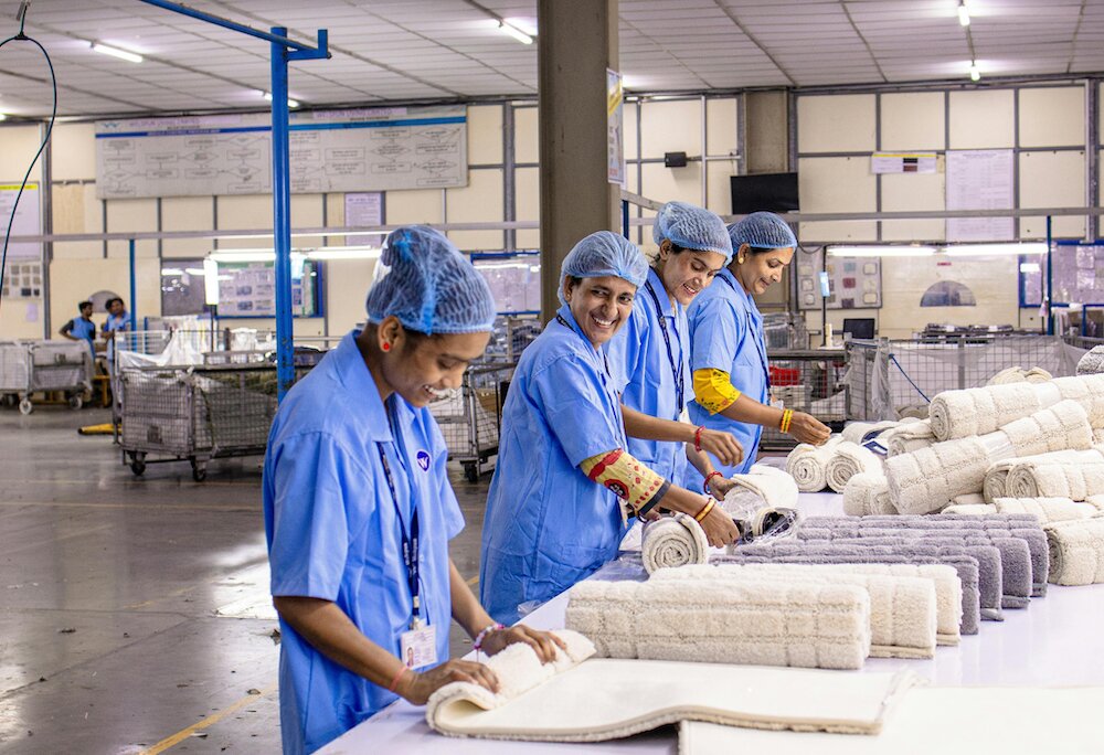 Factory workers folding textile products on a production line in a manufacturing facility, demonstrating industrial operations.